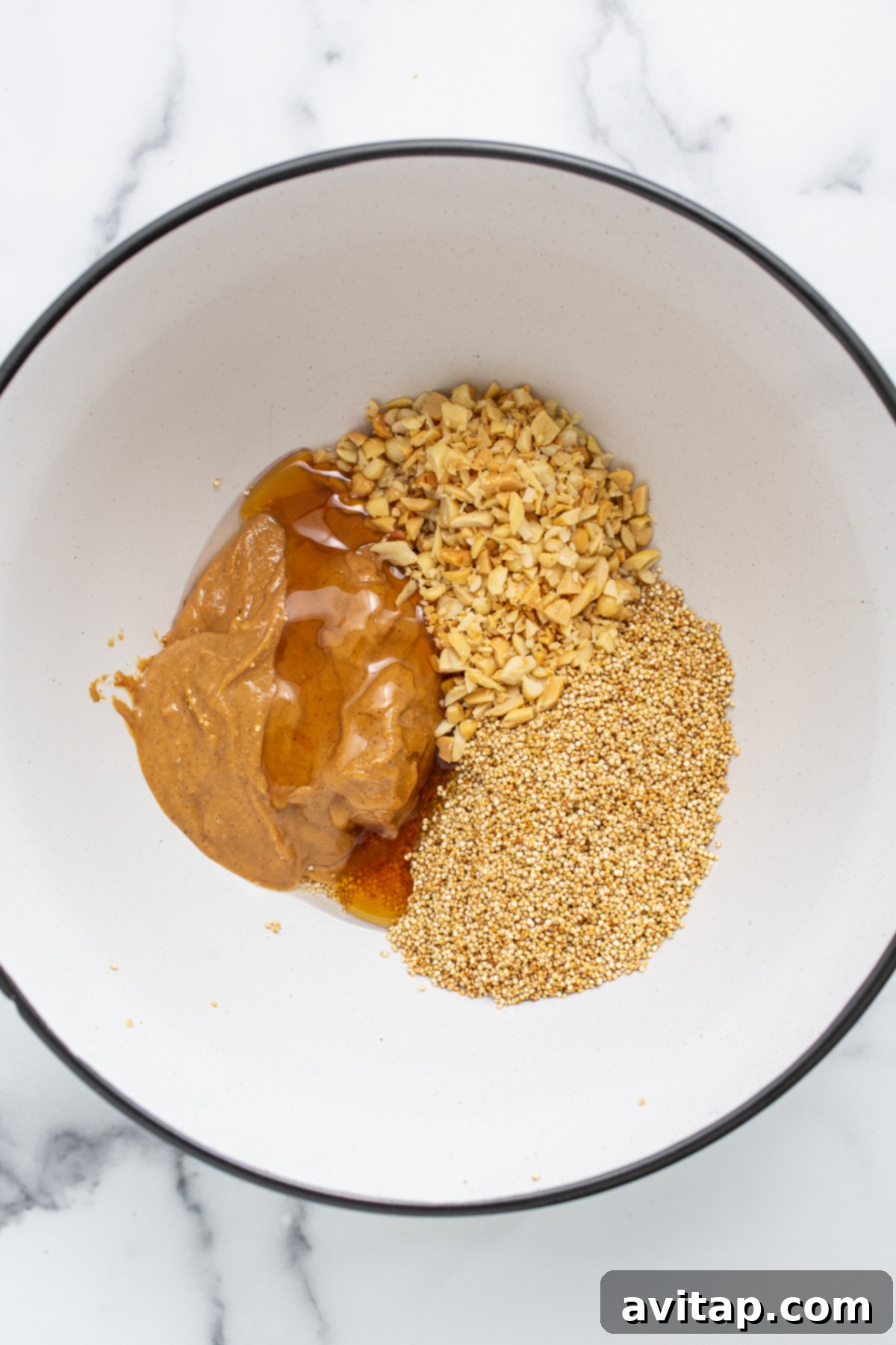 A bowl filled with all the ingredients for peanut butter and jelly quinoa cups before mixing.