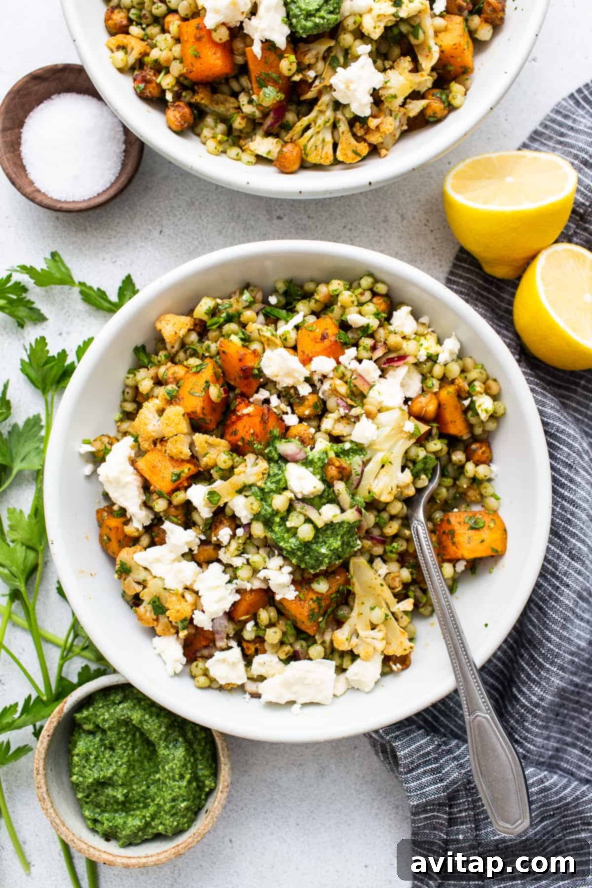 Israeli Couscous Medley 2 A beautifully presented bowl of Israeli couscous salad, garnished with fresh herbs and feta cheese.