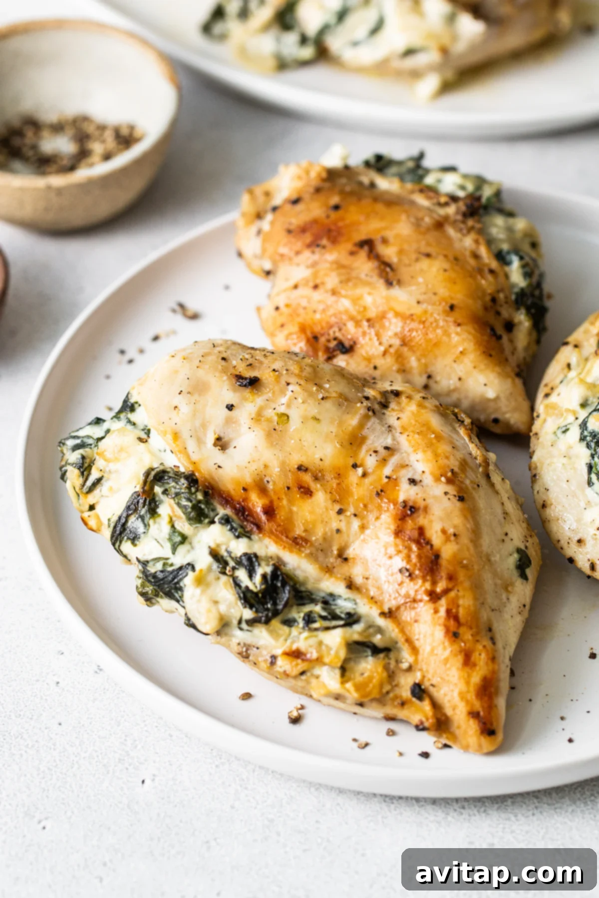 A perfectly cooked spinach stuffed chicken breast on a white plate, showcasing the creamy filling.