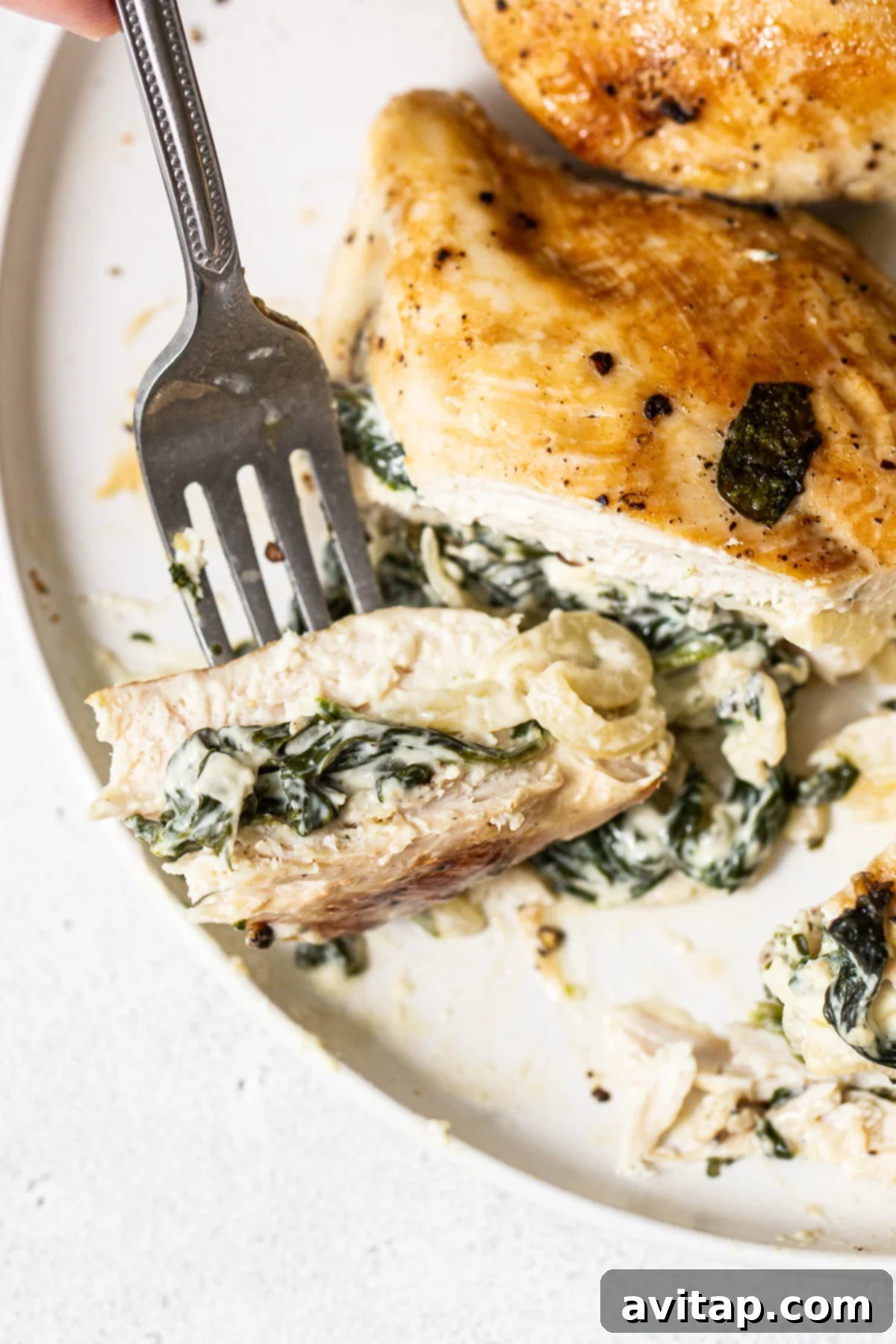 A cross-section of spinach stuffed chicken breast, revealing the creamy, cheesy filling inside a juicy chicken breast.