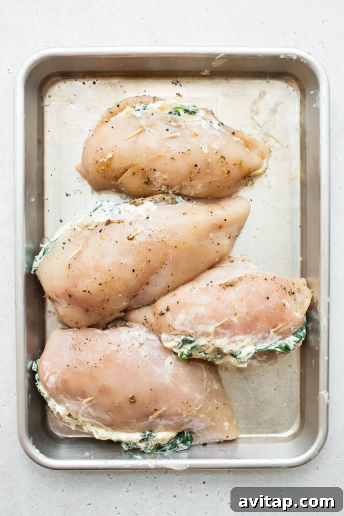 Prepared stuffed chicken breasts arranged neatly on a baking sheet, ready for the oven.