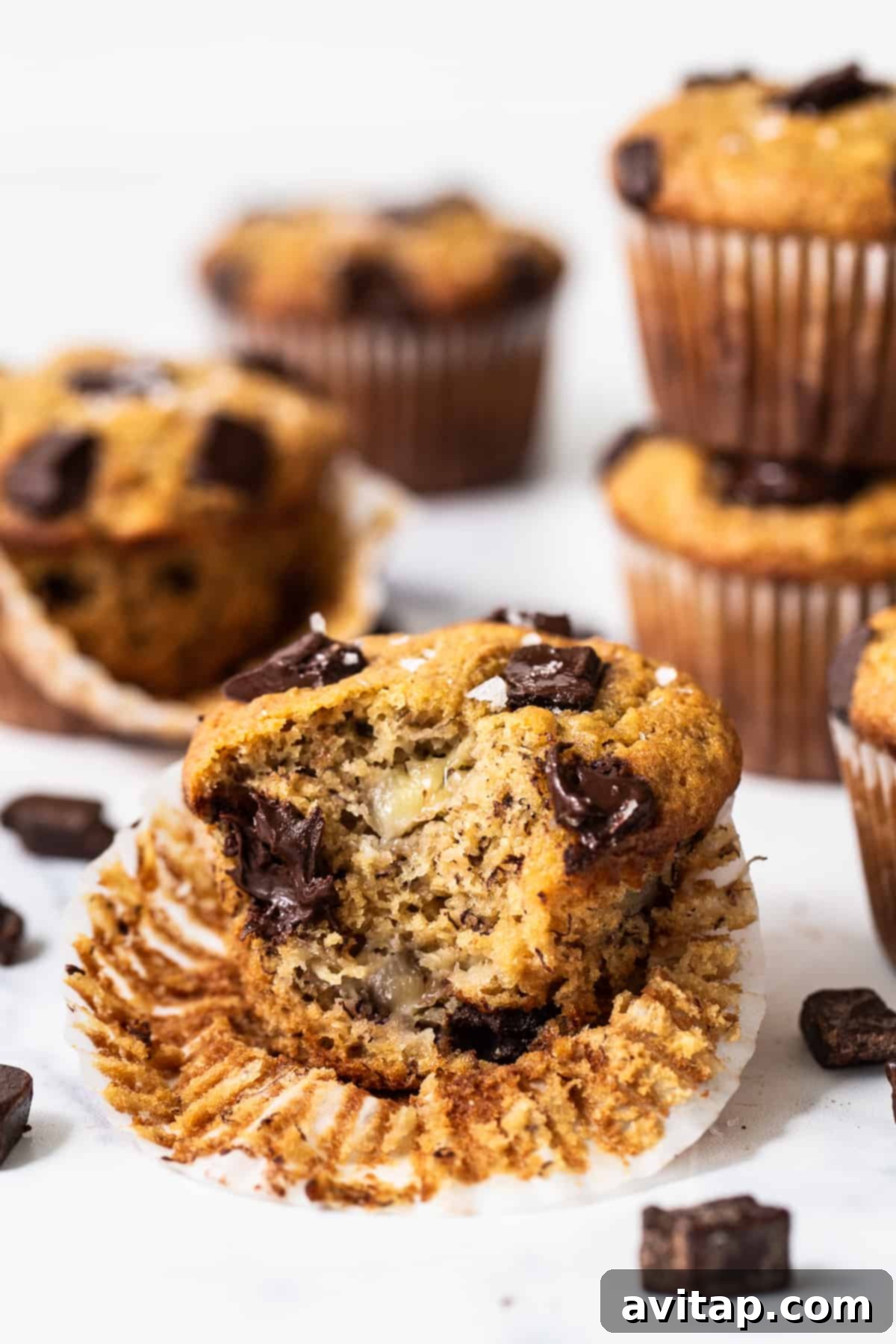 A freshly baked protein muffin with a bite taken out, showing its fluffy interior and chocolate chunks.