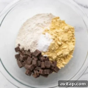 Ingredients for chocolate chip cookie dough in a glass bowl.