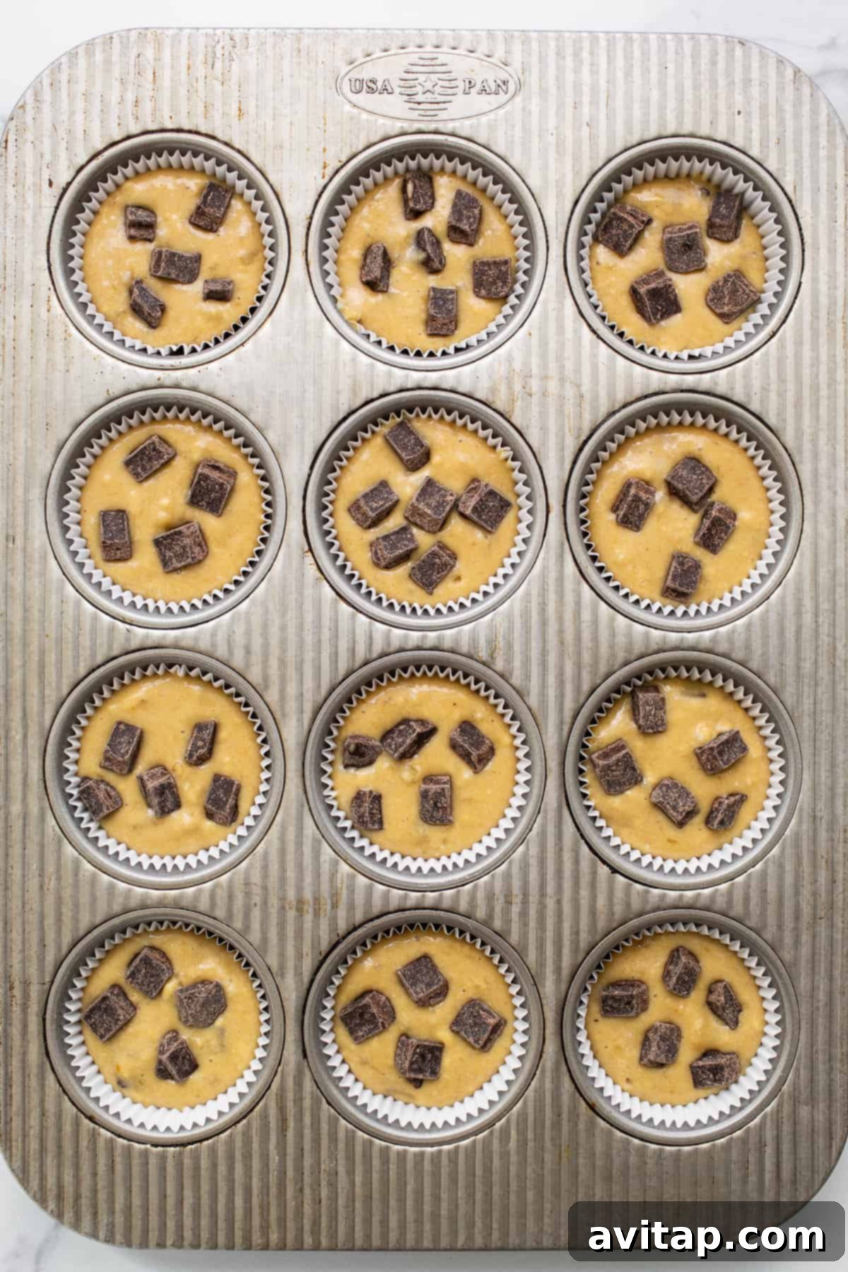 A close-up shot of a plate of freshly baked protein muffins with golden tops and visible chocolate chips.