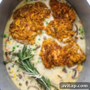 Chicken thighs and vegetables simmering in a skillet with fresh herbs.