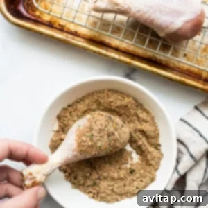 A person is sprinkling seasoning on a chicken wing.