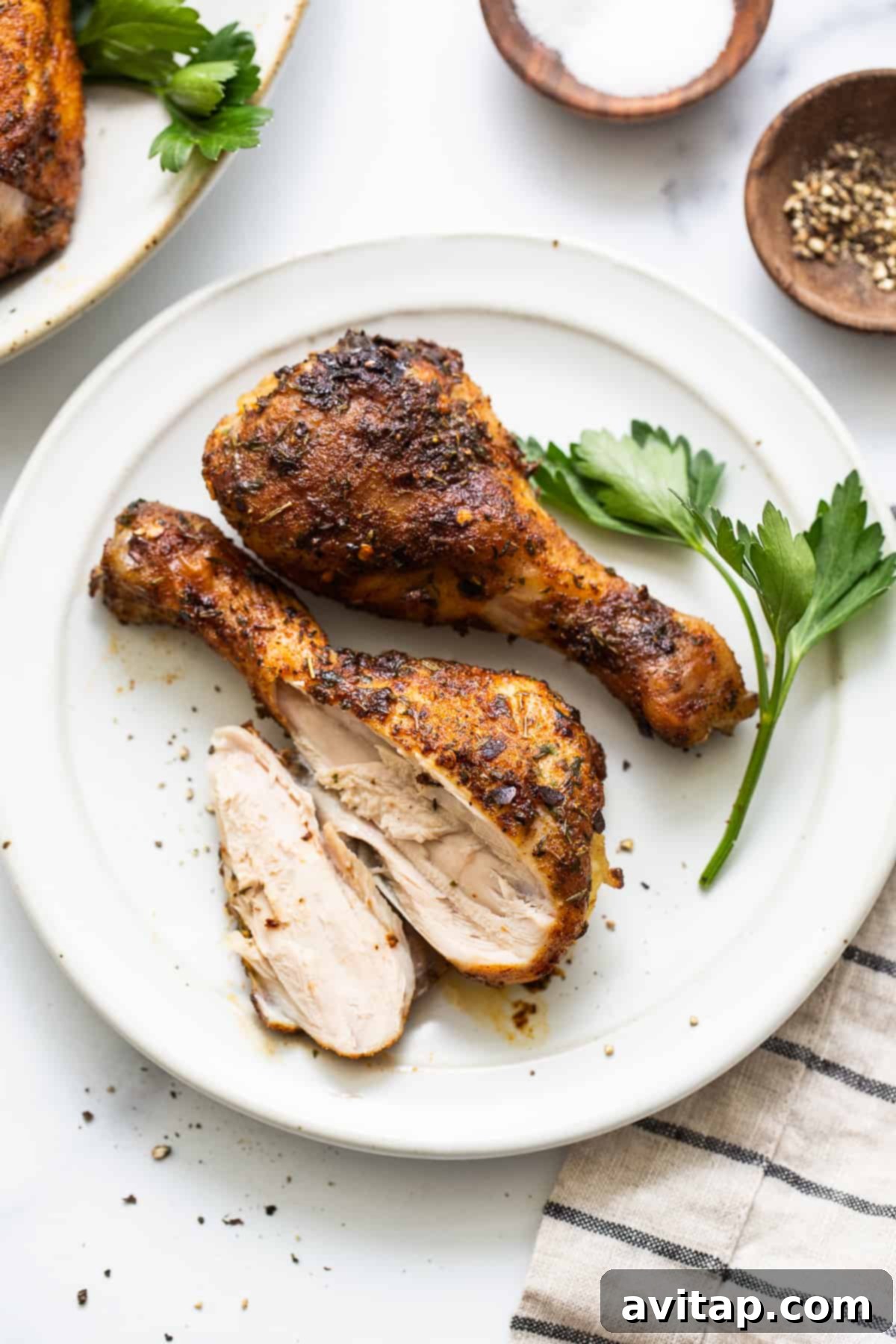 A simple yet appetizing plate of baked chicken legs, accompanied by a side of fresh herbs and a lemon wedge.