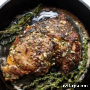 Cast iron steak in a pan with herb butter.