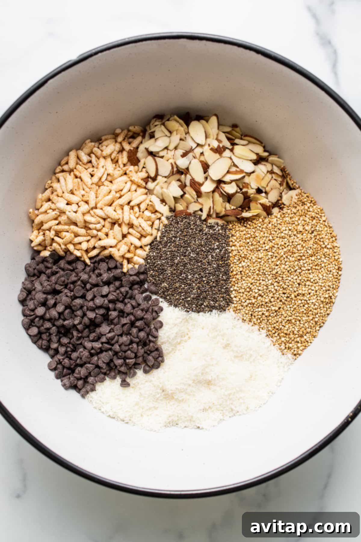 A bowl filled with the dry ingredients for nut and coconut bars, including nuts, seeds, and puffed rice.