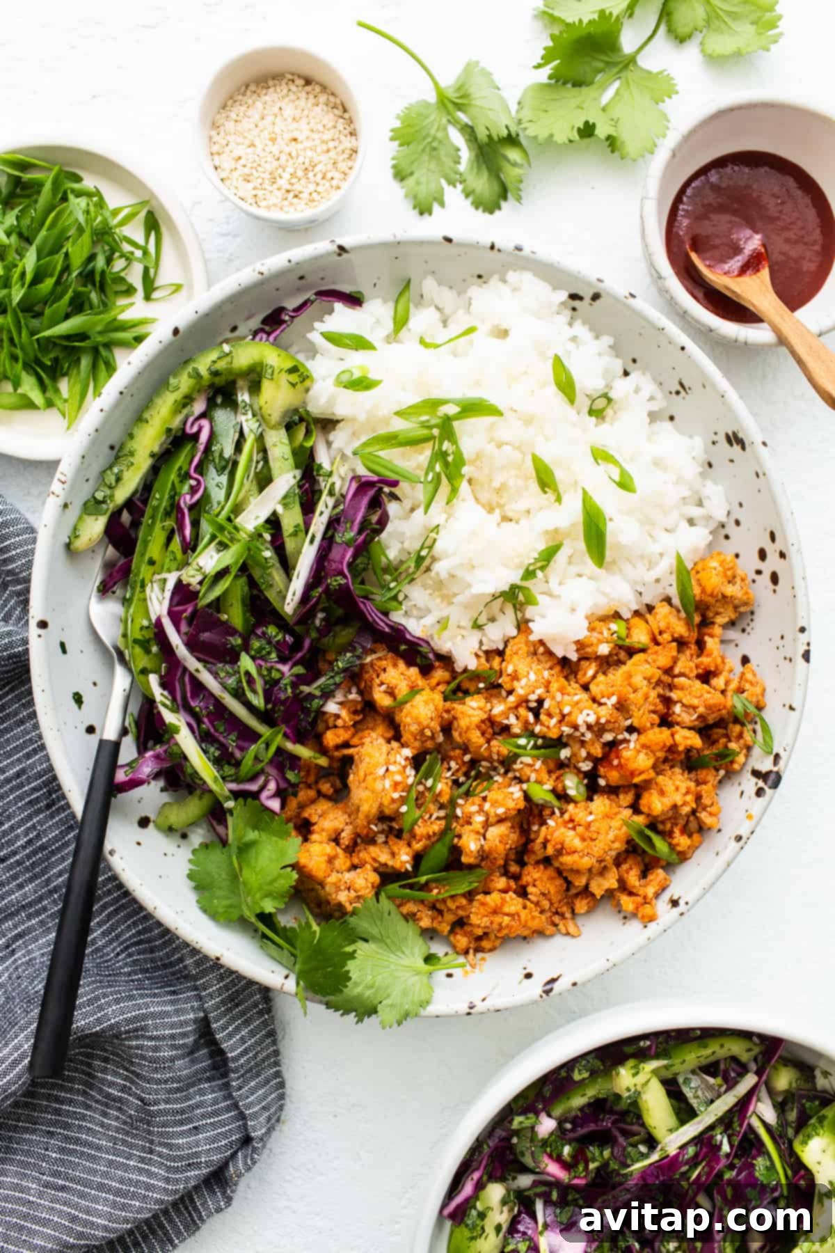 Ground chicken bowls topped with fresh green onions and sesame seeds, showcasing a balanced and colorful meal.