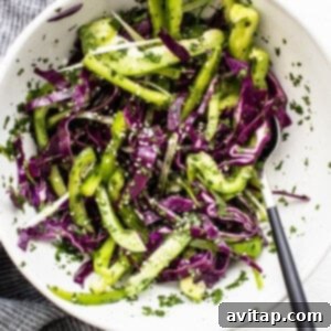 Crisp coleslaw made with red cabbage, green bell pepper, and cilantro in a mixing bowl.