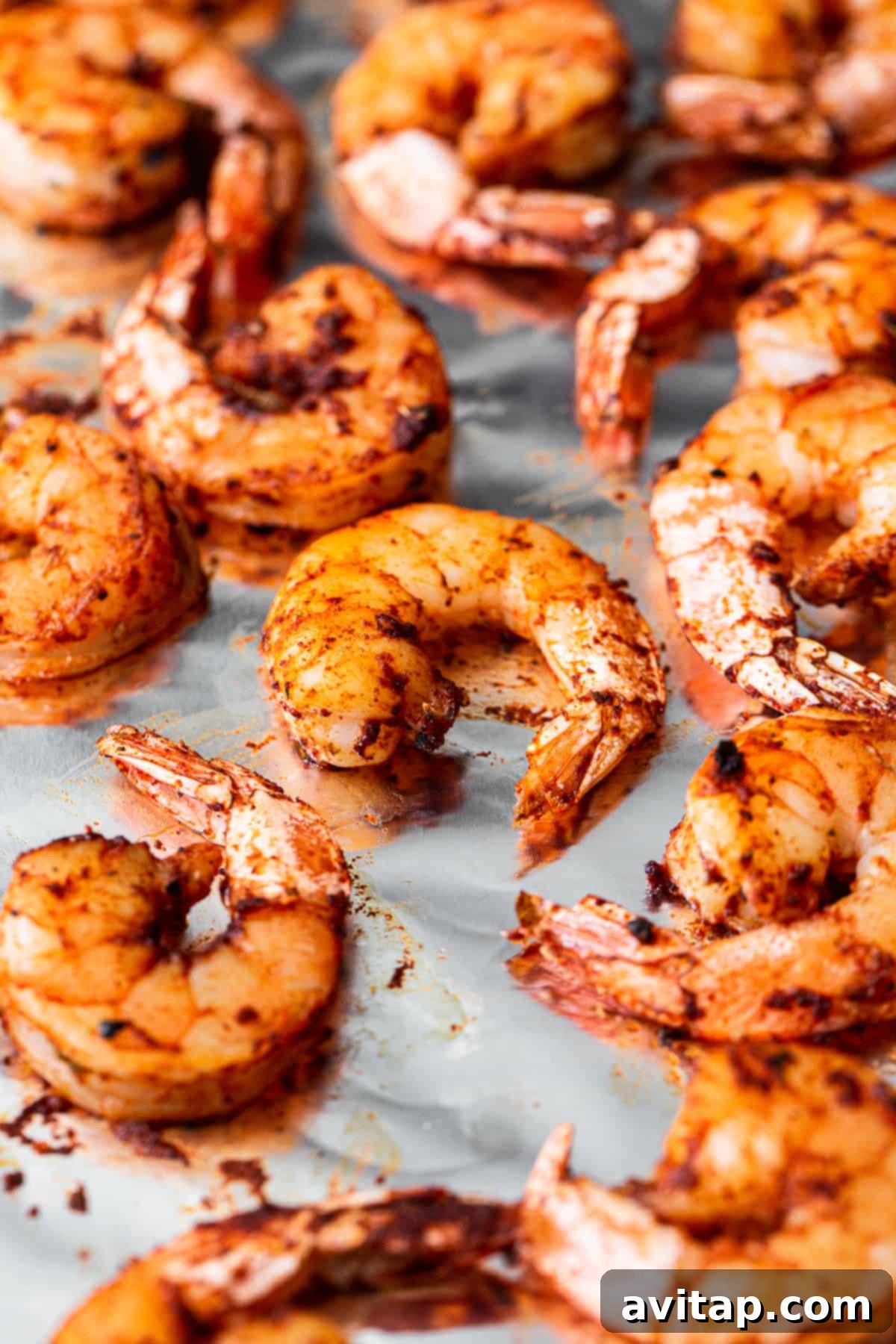 A delicious batch of broiled shrimp on a baking sheet. A close-up shot of perfectly broiled shrimp on a baking sheet, glistening and ready to eat.
