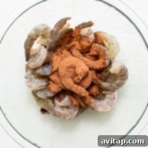 Broiled Shrimp in Minutes 3 Shrimp in a glass bowl with spices on top.
