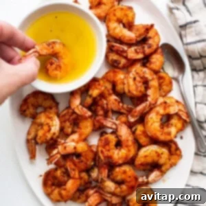Broiled Shrimp in Minutes 6 A plate of grilled shrimp with a hand holding a bowl of olive oil.
