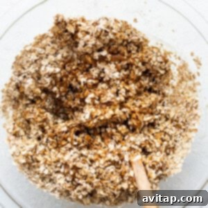 Oats in a bowl with a wooden spoon.