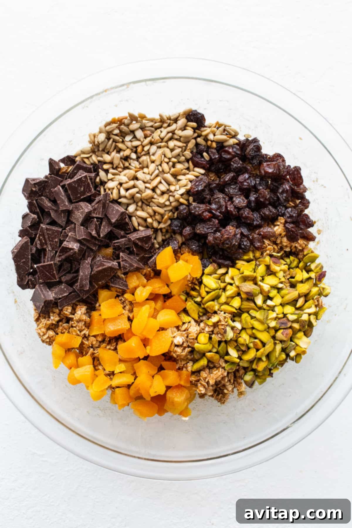 A bowl filled with a delightful mix of trail mix cookie ingredients, showcasing the wholesome nuts, dried fruits, and chocolate pieces.
