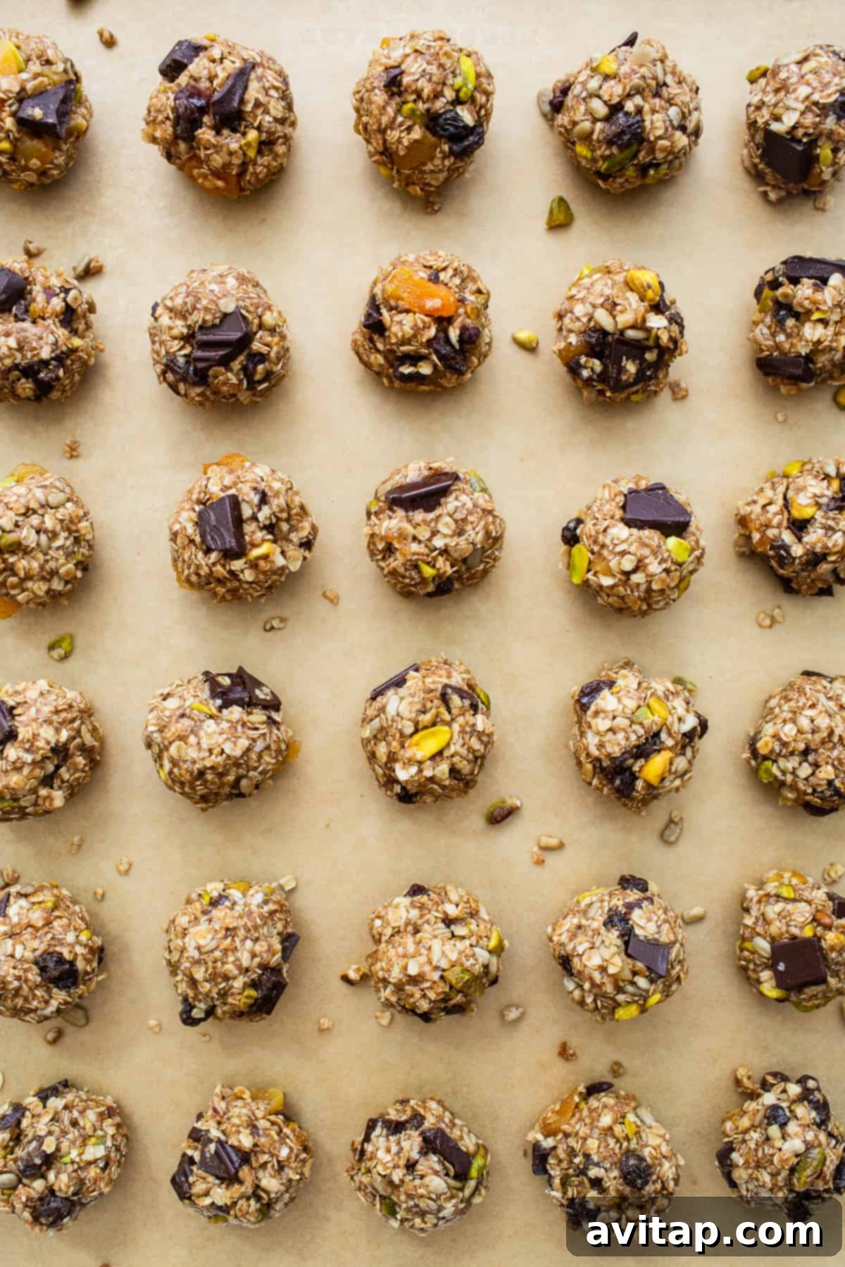 Perfectly scooped trail mix cookie dough balls arranged neatly on a parchment-lined baking sheet, ready for the oven.