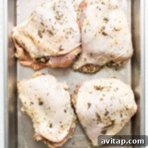 Chicken breasts on a baking sheet with herbs.