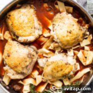 Chicken breasts in a pan with sauce and noodles.