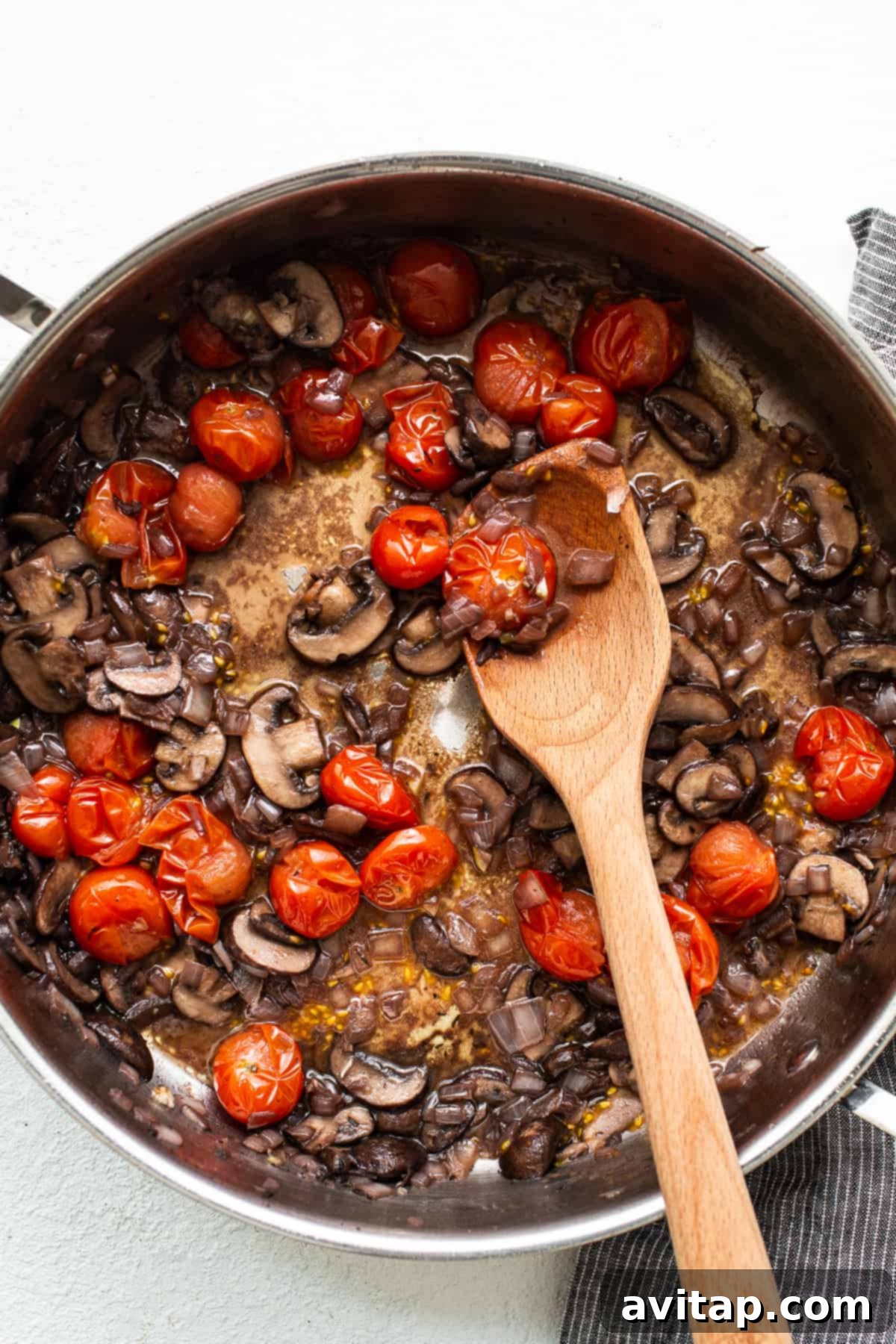Vibrant mushrooms and cherry tomatoes sautéing in a skillet, building the foundation for a delicious pasta sauce.