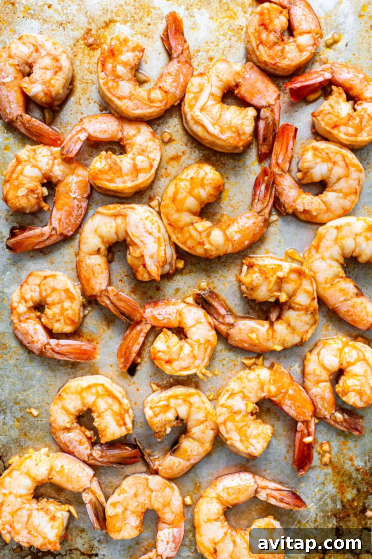 Broiled Spicy Garlic Prawns Perfectly broiled spicy garlic prawns arranged on a baking sheet, ready to serve.
