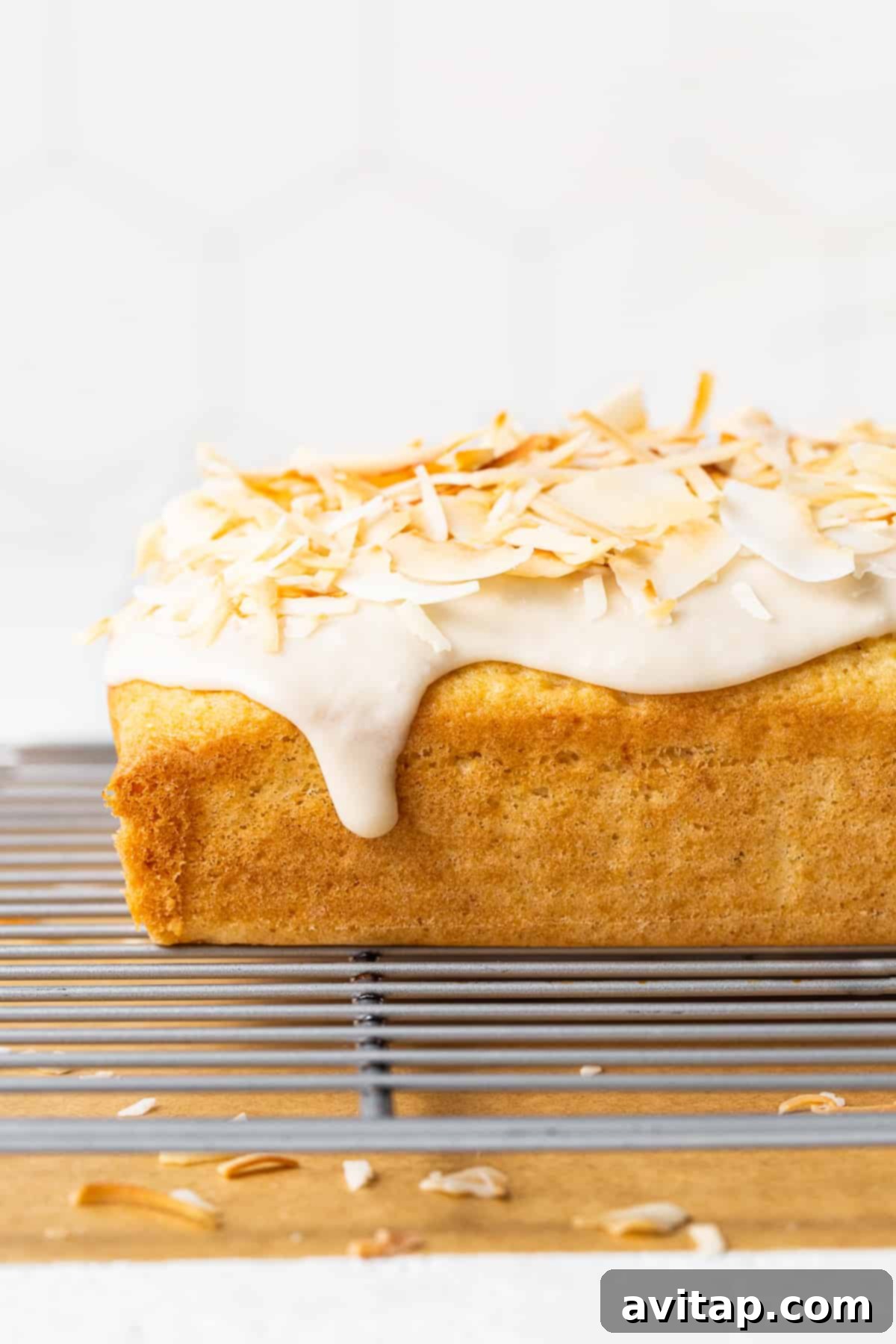 The finished coconut loaf cake resting on a cooling rack, allowing the glaze to set perfectly.