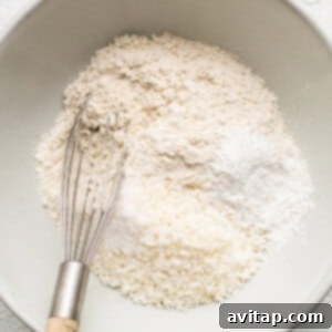 A bowl containing dry ingredients for the coconut loaf cake, freshly whisked and ready to be combined with wet ingredients.