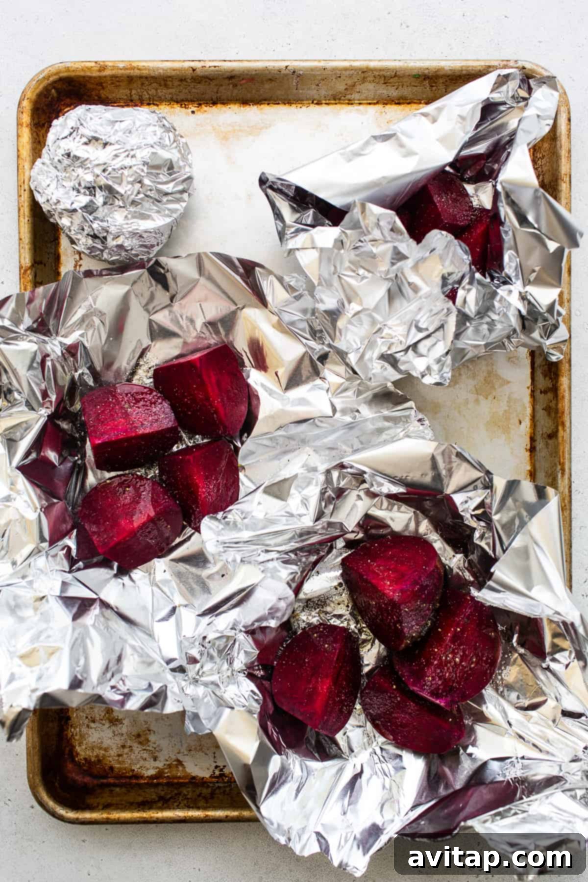Sliced beets neatly wrapped in tin foil, ready for roasting.