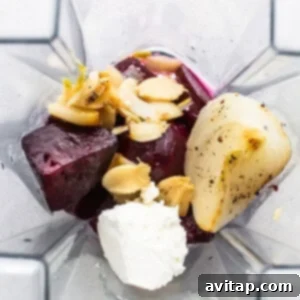 Peeled roasted beets, onion, and garlic being added to a blender for the sauce.