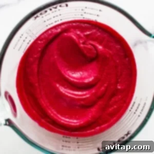 Smooth, vibrant beet puree in a measuring cup, ready to be incorporated into pasta.