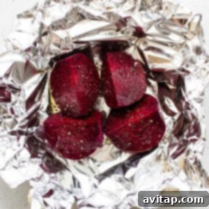 Beets wrapped in foil on a white surface.