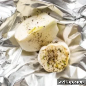 Garlic and onion wrapped in foil with seasonings, ready for roasting.