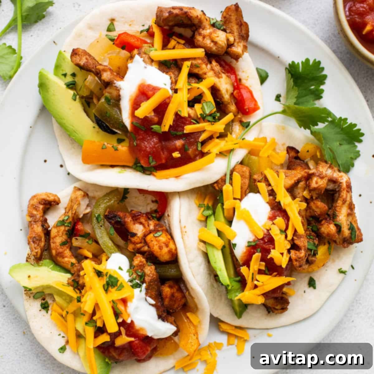 Delicious sheet pan chicken fajitas served on a plate with fresh cheese and avocado slices, ready to eat.