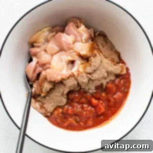 Chicken marinating in a bowl with salsa and fajita seasoning.