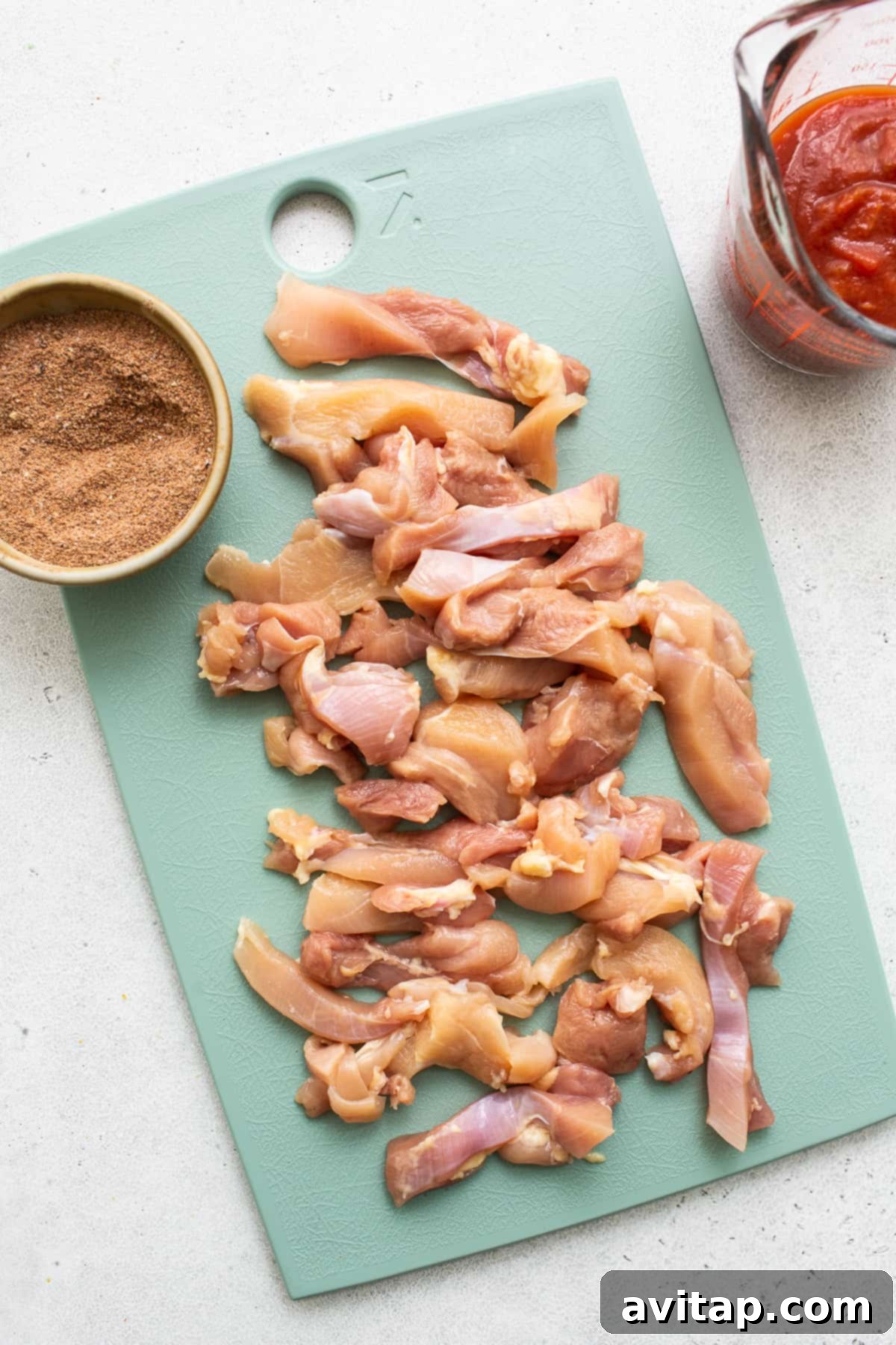 Raw chicken thighs on a wooden cutting board, prepped for slicing into strips for fajitas.