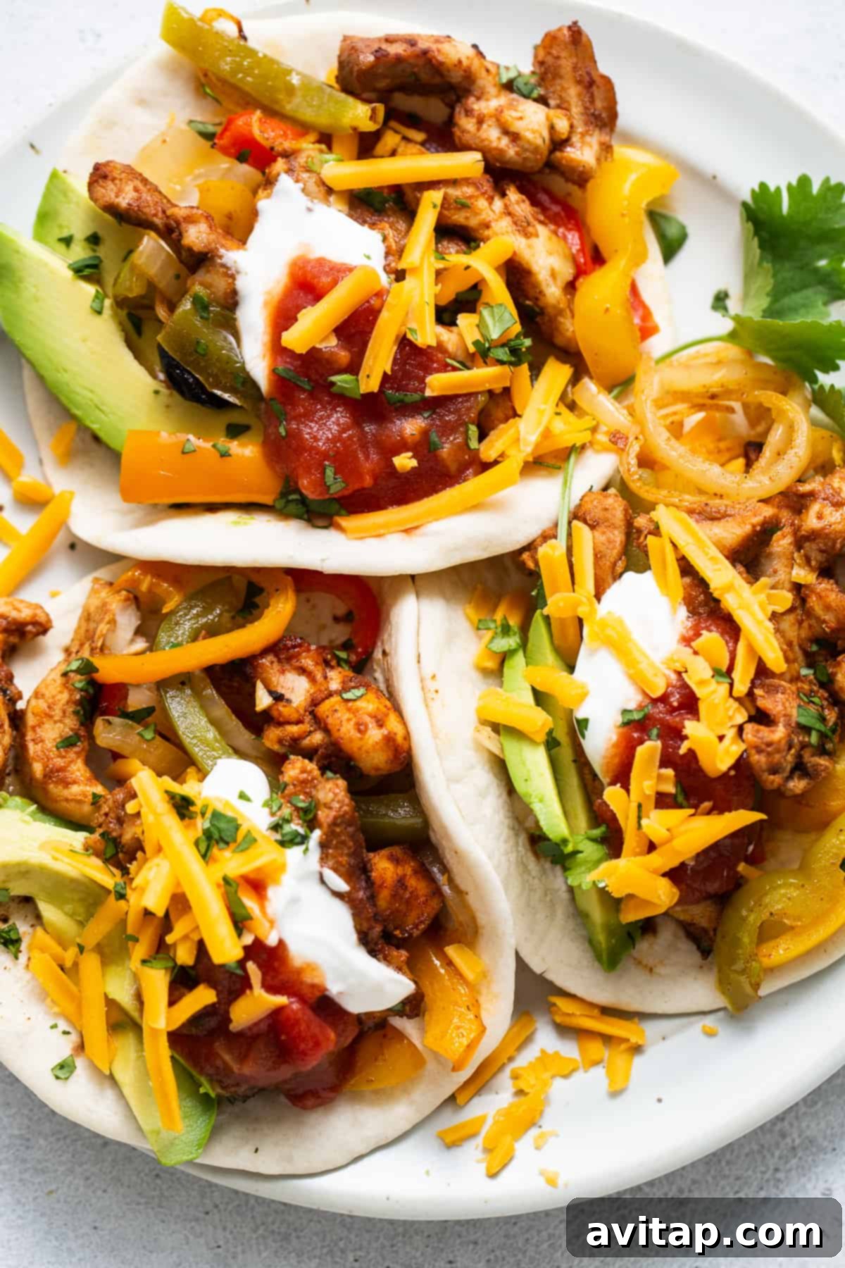 A single chicken fajita, beautifully assembled and ready to eat, on a plate.