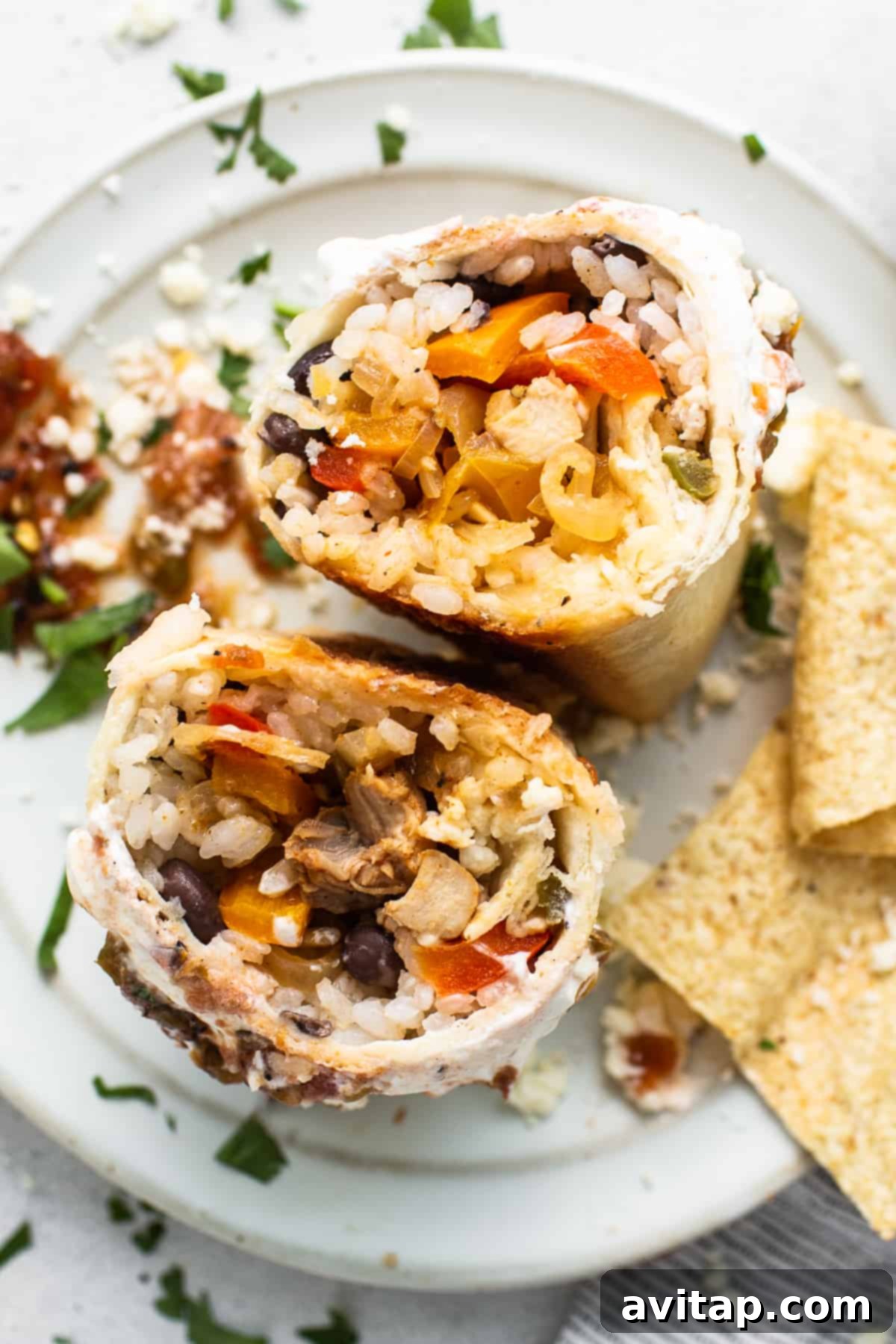 Chicken fajita burrito cut in half on a plate, showing the vibrant fillings.