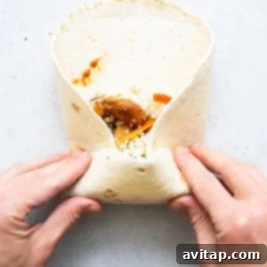 A person holding a burrito in their hands.