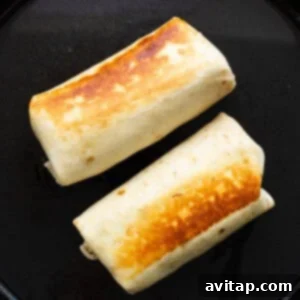 Two burritos on a black plate.