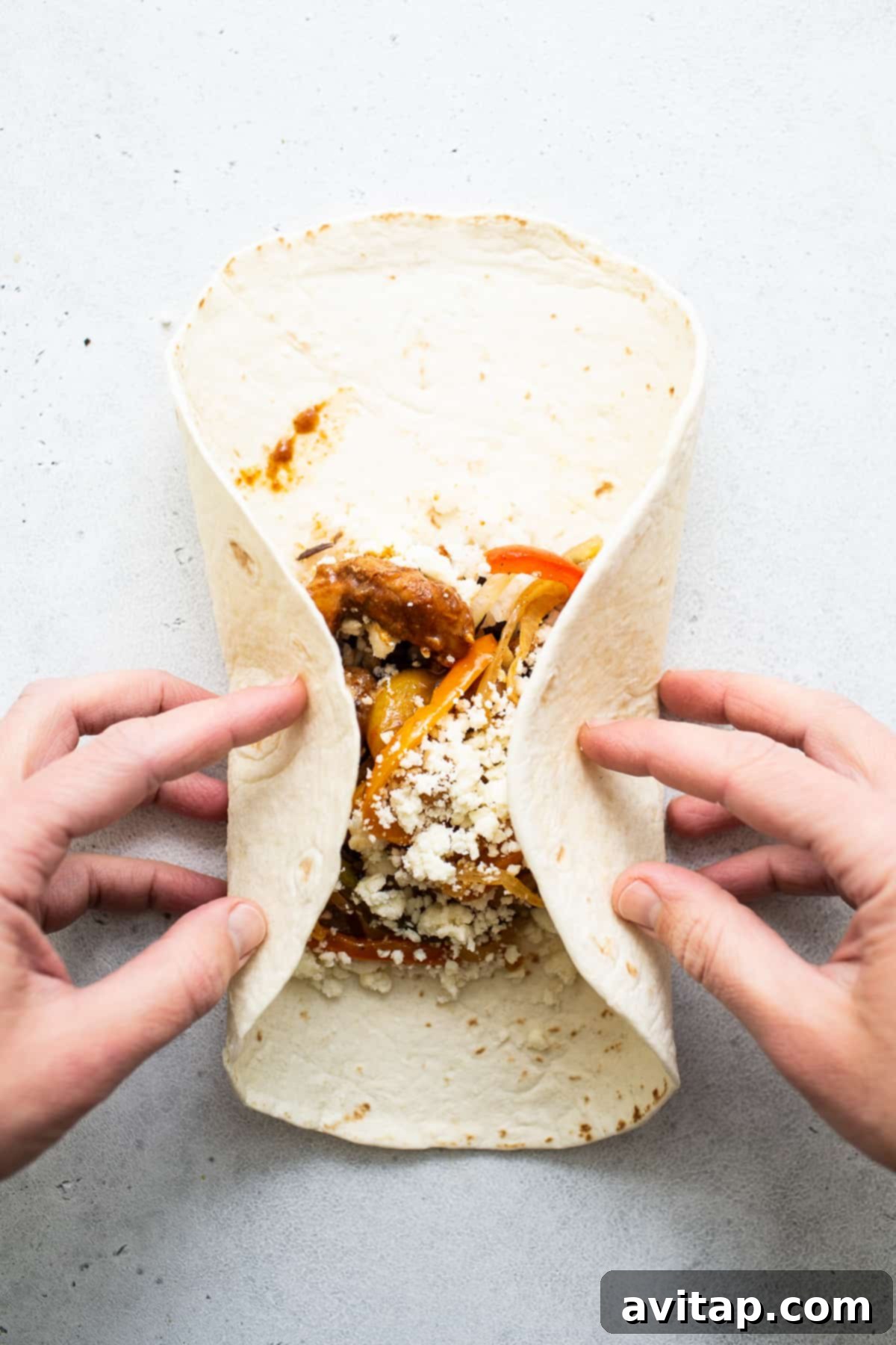 Chicken fajita burrito in the process of being rolled up.