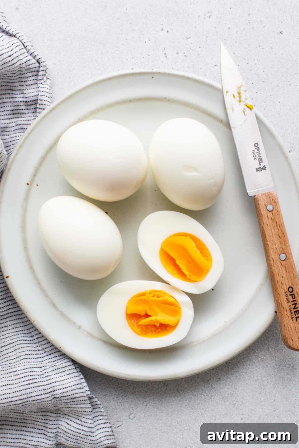 A close-up of a perfectly peeled air fryer hard boiled egg on a simple white plate.
