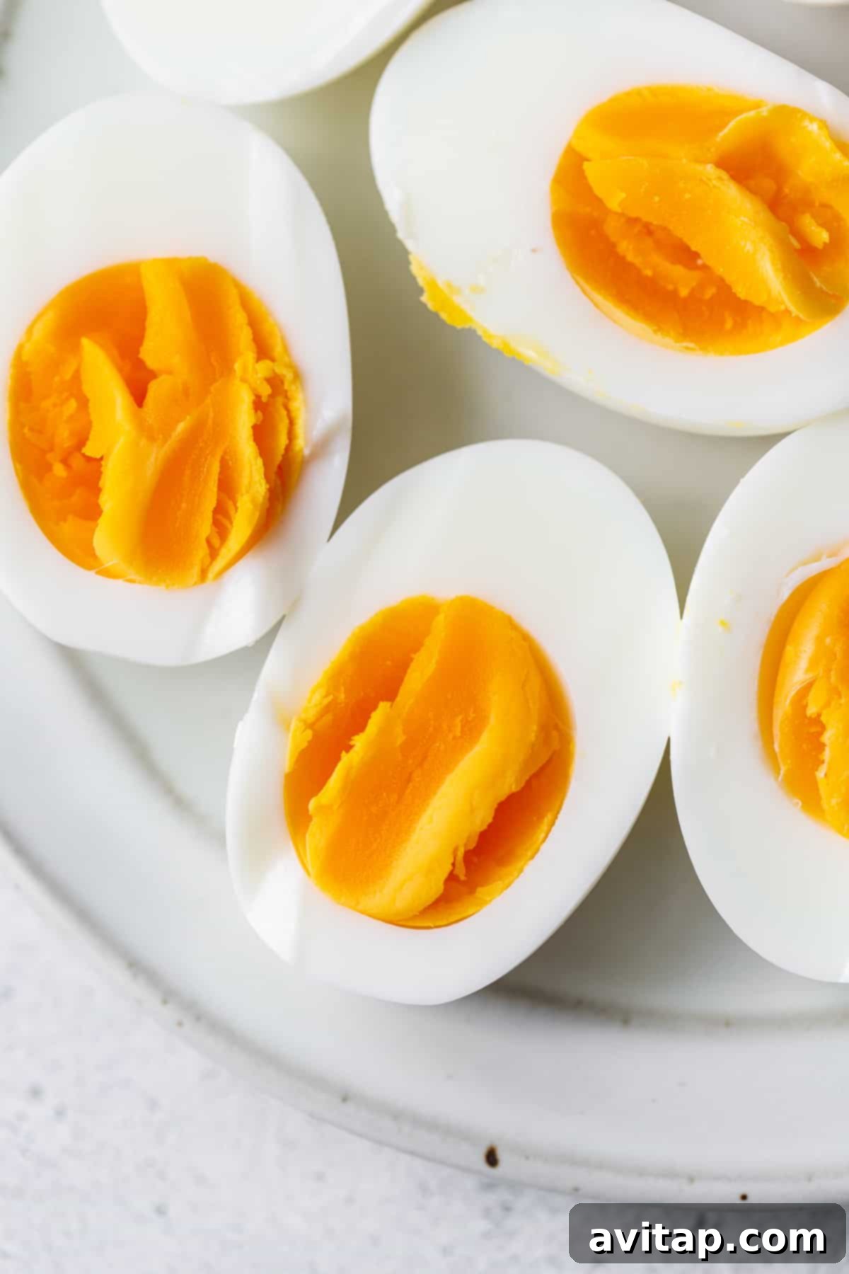 Close-up of two air fryer hard boiled eggs, perfectly cut in half to show their firm, yellow yolks.