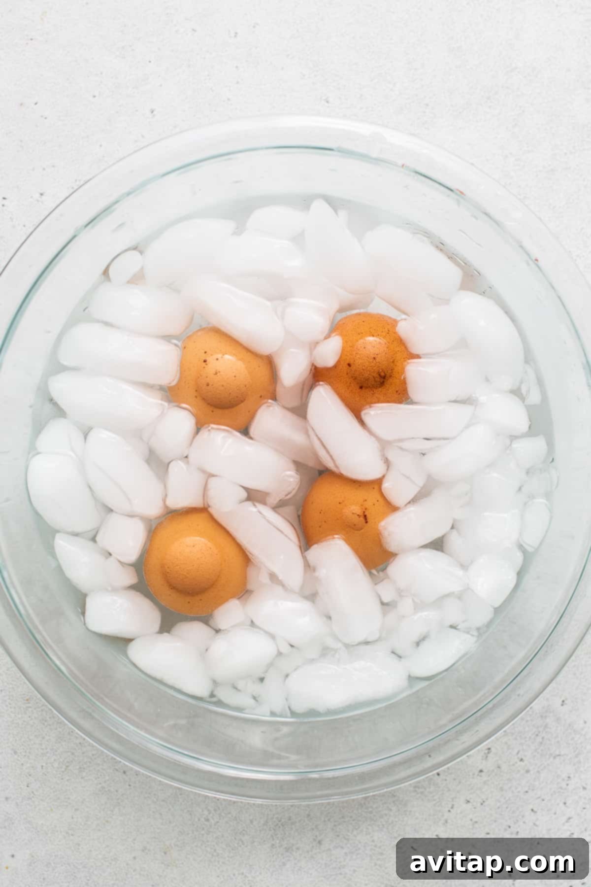 Hard boiled eggs cooling in a bowl of ice water, a crucial step for easy peeling.