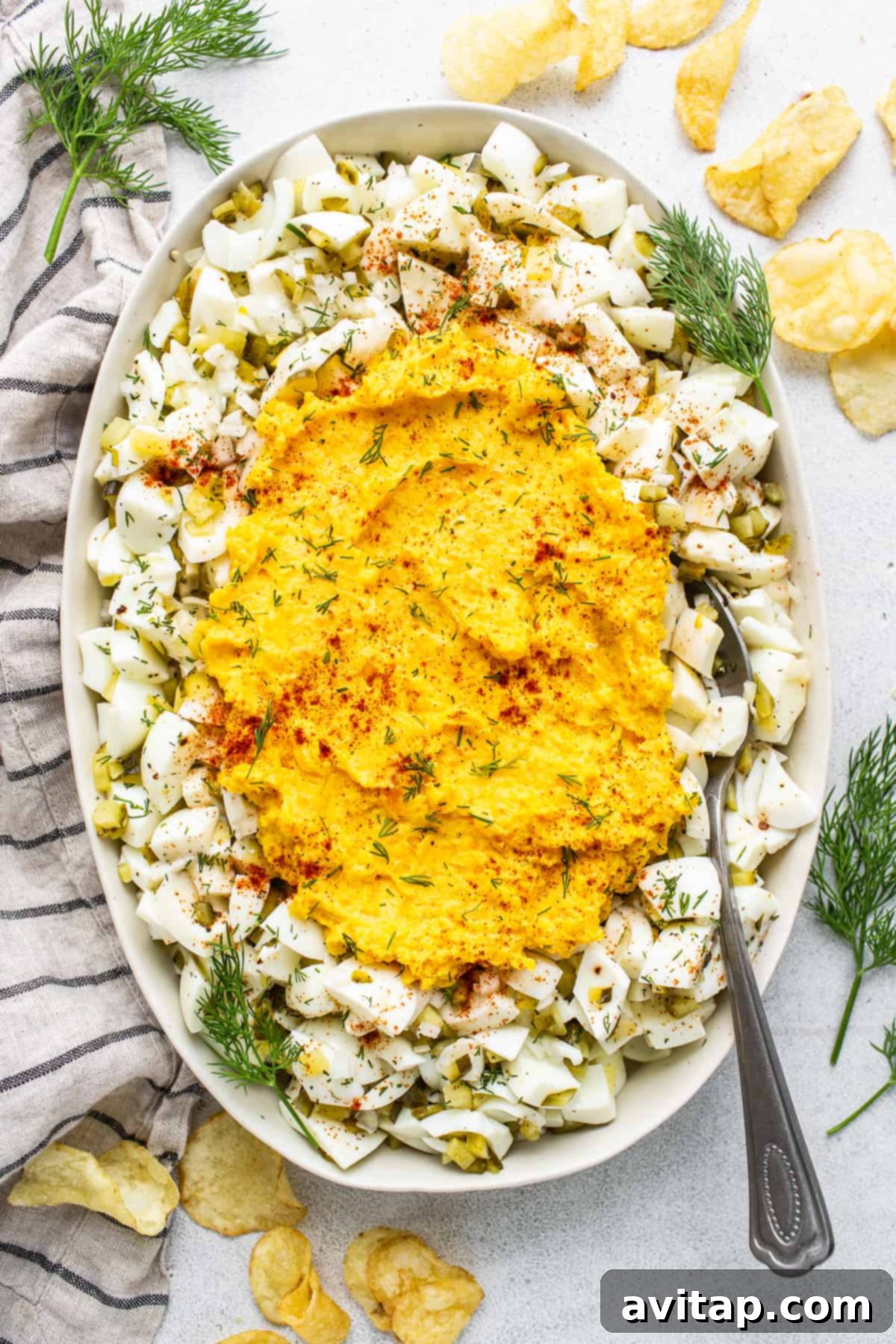 A beautifully presented bowl of creamy deviled egg salad, garnished with vibrant paprika and fresh dill, ready to be served.