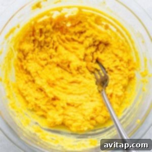 A bowl of yellow mashed potatoes with a fork in it.