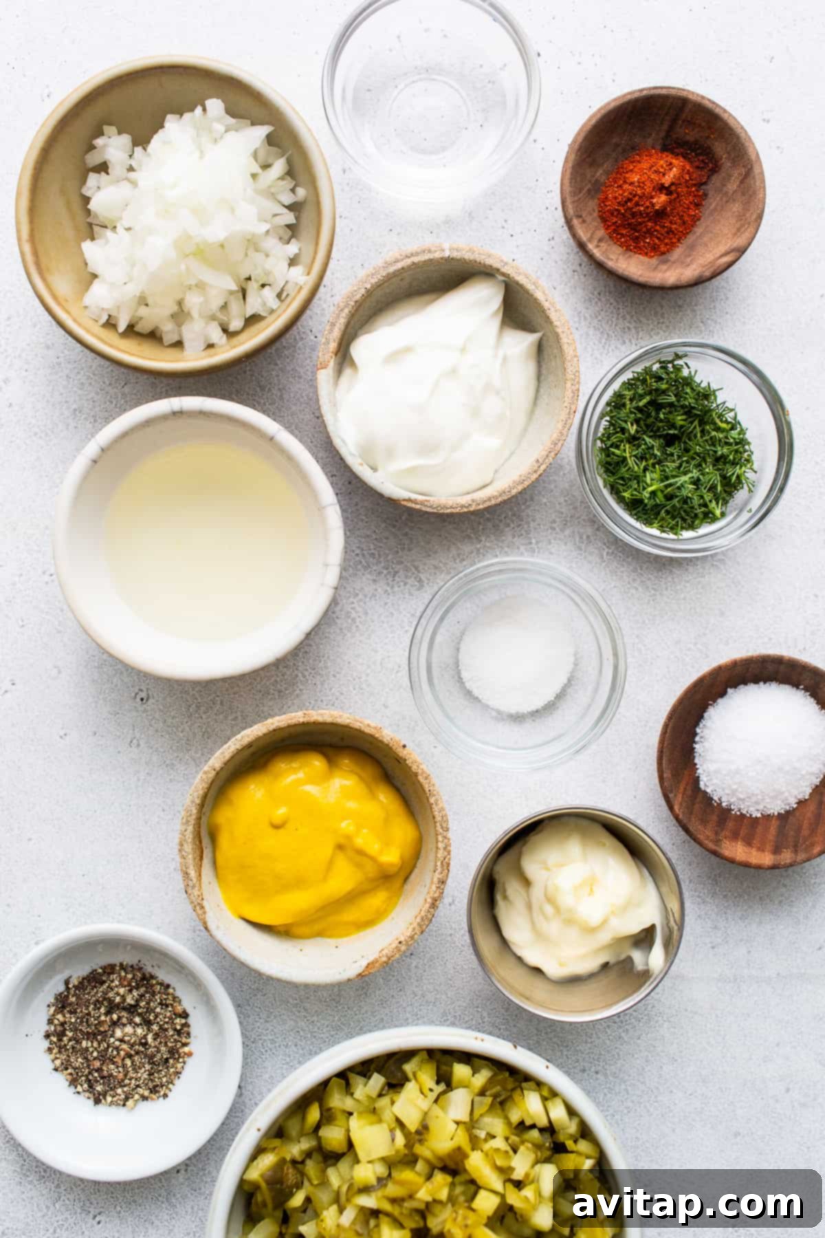 Bowls displaying individual fresh ingredients for deviled egg salad: perfectly hard-boiled eggs, finely chopped dill pickles, minced white onion, creamy mayonnaise, tangy yellow mustard, and rich Greek yogurt.