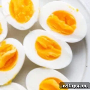 A cluster of perfectly hard-boiled eggs on a white plate, showcasing their smooth shells, ready for peeling.