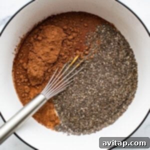 Chia seeds and cocoa powder are mixed into wet ingredients in a bowl with a whisk.