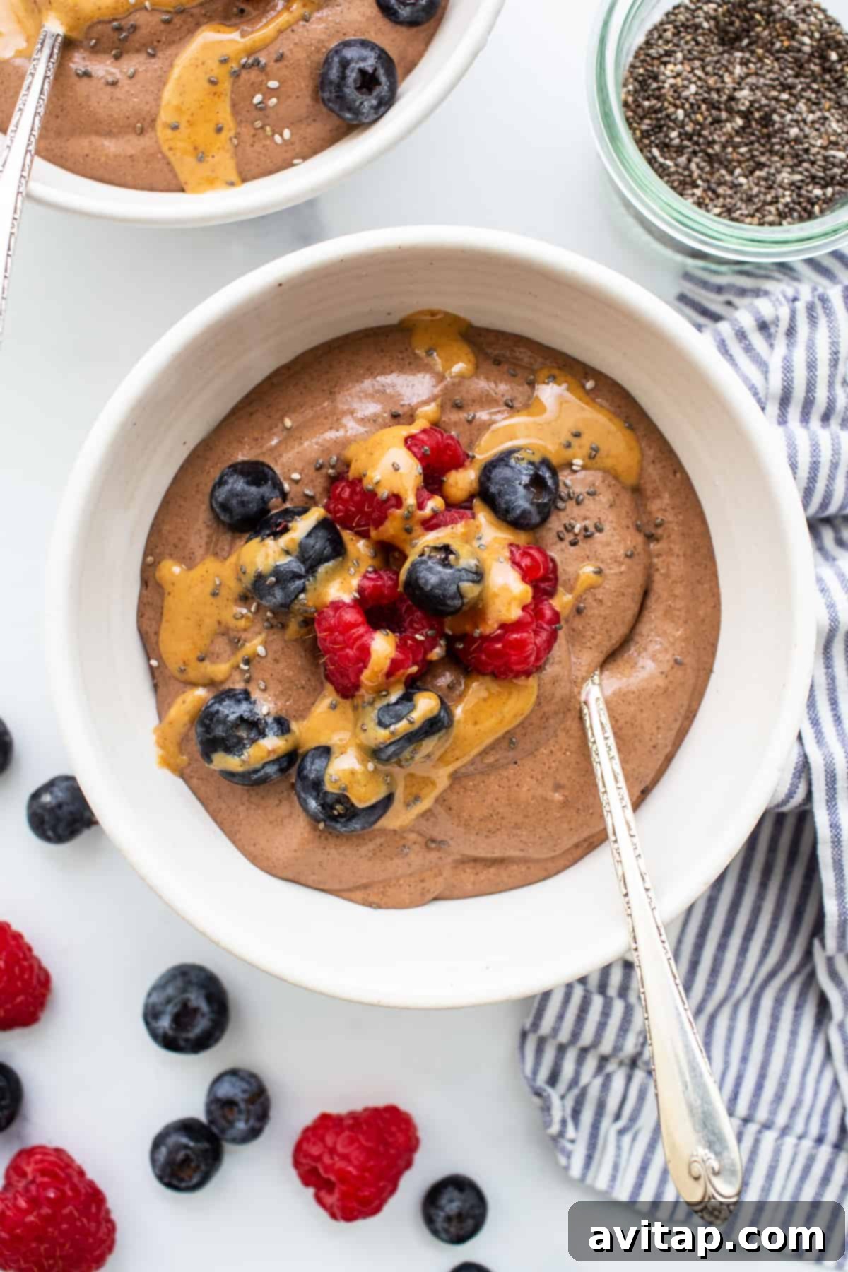 A visually stunning bowl of blended chia seed pudding, generously topped with an assortment of fresh berries and a drizzle of creamy peanut butter.