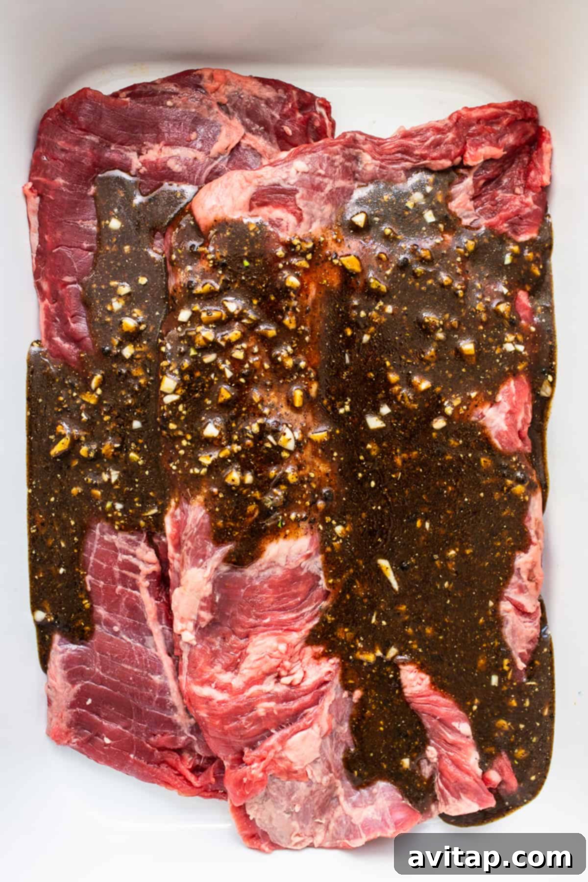 Skirt steak marinating in a pan, soaking up delicious flavors.